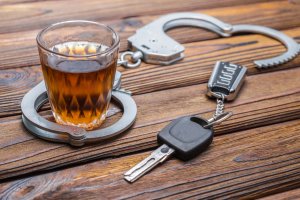 Concept drunken driving. Handcuffs, a glass of alcohol, car keys.