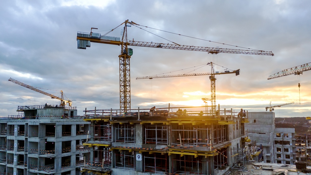 Two tall construction cranes over work site