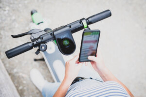 Close-up of person unlocking rentable e-scooter with phone