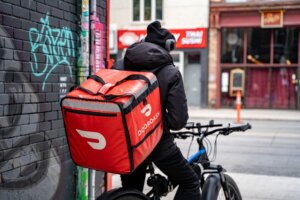Image of a bicycle courier with DoorDash delivery bag