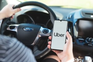 Stylized image of a driver holding cell phone with Uber logo on screen