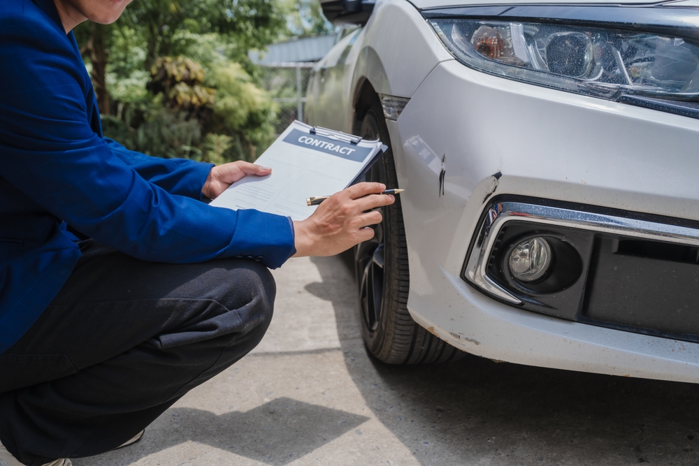 Claims adjuster reviews damage to vehicle after car accident